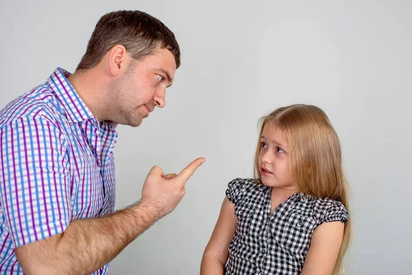 Shot of an angry father scolding or punishing a little daughter.