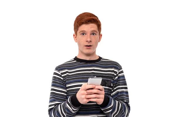 Un niño adolescente está de pie con un teléfono y emocionalmente juega — Foto de Stock