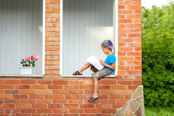Plně dlouhý portrét vážného malého chlapce sedícího na verandě — Stock fotografie