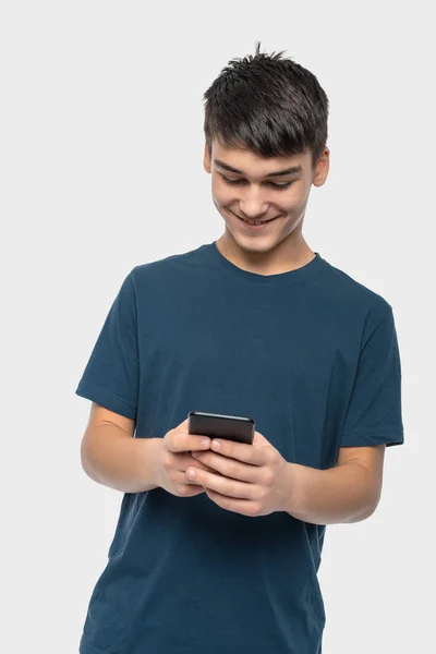 Мальчик-подросток стоит с телефоном и эмоционально коммуникативен — стоковое фото