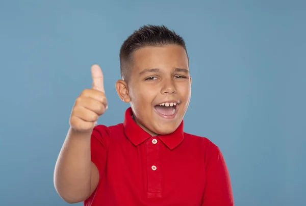 Een jonge lachende jongen geeft je een goed gebaar tegen blu — Stockfoto