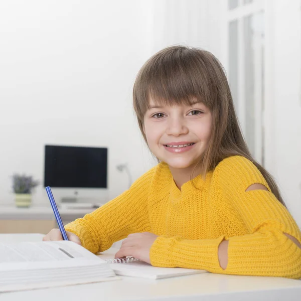 Блондинка сидить за столом вдома і робить домашнє завдання — стокове фото