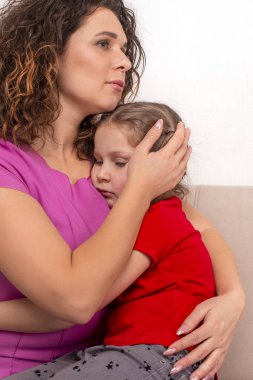 Mather ve kızının kanepede oturup birbirlerine sarıldıkları bir fotoğraf. Anne, üzgün küçük bir kızı sakinleştirir. Annenin sevgisi.