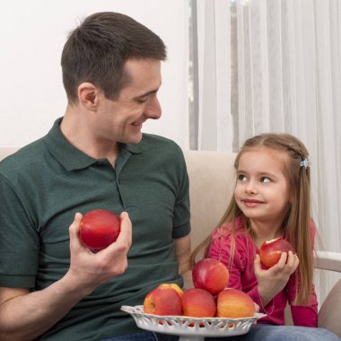 Küçük kızı olan genç bir adam evde vakit geçiriyor. Elma yemeyi seviyorlar. Ailedeki erkeklerin modern rolü..