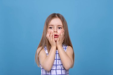 Stüdyoda fotokopi alanı olan, mavi arka planda, uzun sarı saçlı, ciddi bir kızın yarım boy portresi. Bir şeye üzüldü.