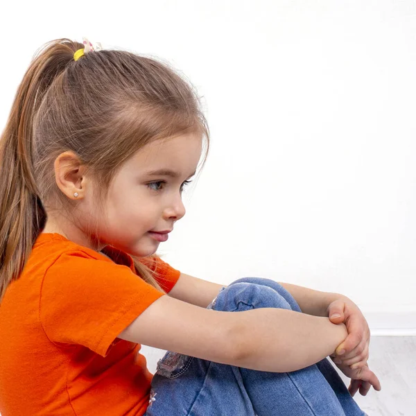 Foto Una Niña Sonriente Con Camisa Naranja Vaqueros Sentados Suelo — Foto de Stock