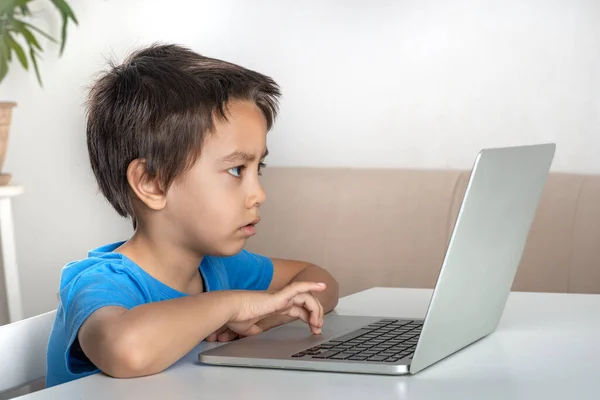 Tiro Menino Sério Sentado Uma Mesa Casa Navegando Internet Laptop — Fotografia de Stock