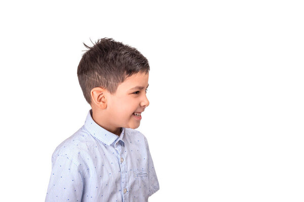 Фотография веселого мальчика в синей рубашке, смеющегося над чем-то и смотрящего в сторону на белом фоне в студии
