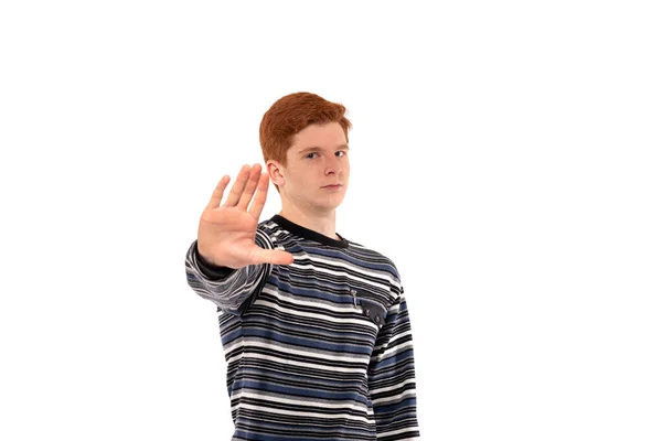 一个红头发 手举着手势的认真的小伙子在工作室里展示了在白色背景下停止吸毒 战争或污染 — 图库照片