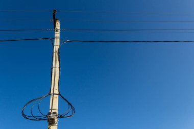 Mavi gökyüzüne karşı kablolu elektrik direği