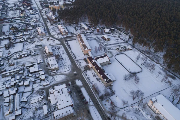 Schule und Schuleisbahn. Luftaufnahme des Dorfes Oktyabrski mit Straßen und Wald. Russland. Winter, Abend, Sonnenuntergang — Stockfoto