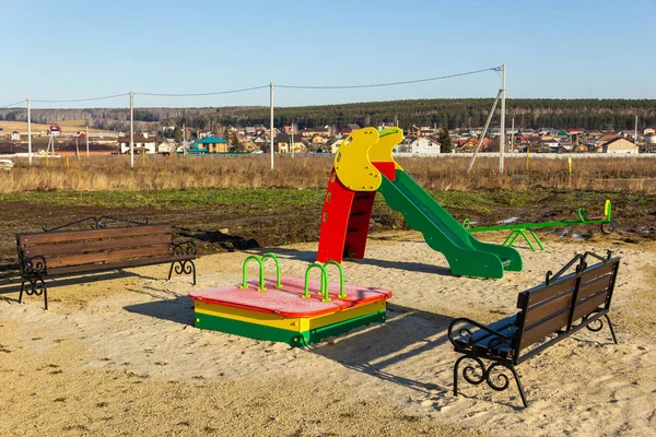Spielplatz im Hüttendorf im Bau. Im Hintergrund das Dorf. Herbst, sonniger Tag lizenzfreie Stockbilder