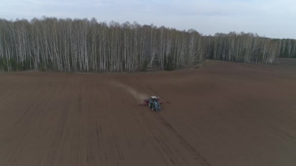 Een Tractor Ploegt Een Enorm Veld Achtergrond Van Het Bos — Stockvideo