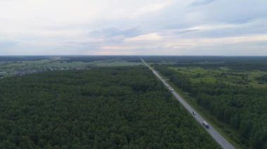 Tepelerin yakınındaki yaz orman yolunda bir kamyon ve arabaların drone görüntüsü. İyi akşamlar.