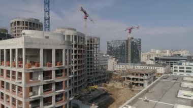 Şehirdeki yüksek binaların ve vinçlerin havadan çekilmiş görüntüleri. Kentsel altyapı geliştirme. Yaz güneşli bir gün.
