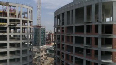 Şehirdeki yüksek binaların ve vinçlerin havadan çekilmiş görüntüleri. Kentsel altyapı geliştirme. Yaz güneşli bir gün. Kamera sağa döner.