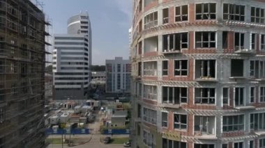 Şehirdeki yüksek binaların ve vinçlerin havadan çekilmiş görüntüleri. Kentsel altyapı geliştirme. Yaz güneşli bir gün. Kamera sağa döner.