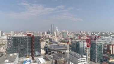 Şehrin arka planında yüksek binaların ve inşaat vinçlerinin havadan çekilmiş görüntüleri. Kentsel altyapı geliştirme. Yaz güneşli bir gün.