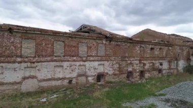 08 numara. Göletin kıyısındaki tuğla boruyla eski tuğla binanın havadan görünüşü mahvoldu. Köyün yakınlarında. Bahar, bulutlu. Rusya, Chebyabinsk bölgesi, Kaslinsky bölgesi, Vozdvizhenka köyü