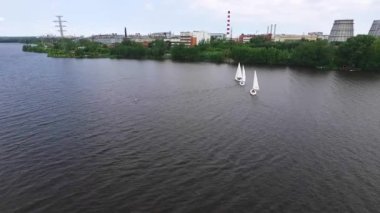 Yarış. Arka planda fabrikalar olan bir gölette yelkenli manzarası. Yaz, güneşli