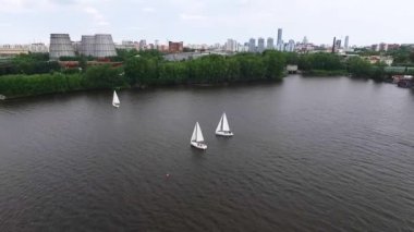 Şehir göleti üzerinde fabrikalar ve arka planda şehir olan yelken yatının havadan görünüşü. Yaz güneşli bir gün