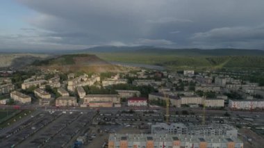 Şehir manzarası alçak binalar, stadyum ve okul. Arabalar yollarda gider. Şehrin yakınlarında büyük bir maden ocağı ve maden ocağı var. Ural Dağları 'nın dışında. Yaz, akşam. Rusya, Chelyabinsk bölgesi, Satka şehri