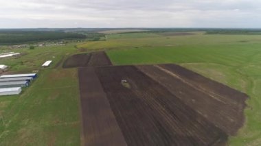 Traktörün hava görüntüsü ekin için tarla eker. Döner harrow sabanla tarım traktörü ekim için arazi hazırlıyor. Disk kirişleri tarafından tarım arazisi. Uzaktan bir kamera bir traktöre yaklaşıyor. Çiftliğin yanında.