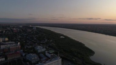 Akşam şehri Tomsk 'un günbatımındaki hava manzarası. Tom River ve Tomsk bölgesinin yönetim binası. Arabalar yollarda gider. Yaz sıcak akşamı. Rusya, Sibirya, Tomsk bölgesi