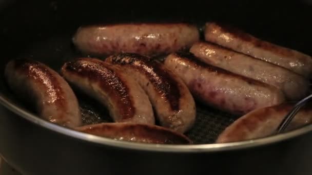 Brats sizzling in dark pan — Stock Video