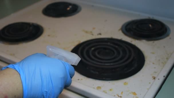 Mano en guante azul rociando limpiador en estufa sucia — Vídeo de stock