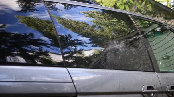 Rinsing windows of gray van with hose — Stock Video