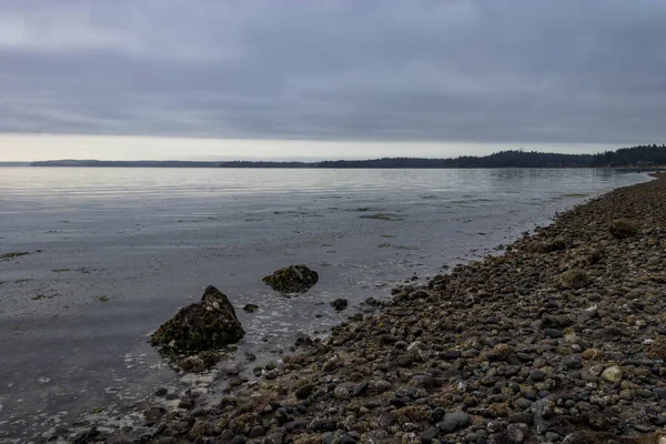 bulutlu bir plaj boyunca büyük taşlar