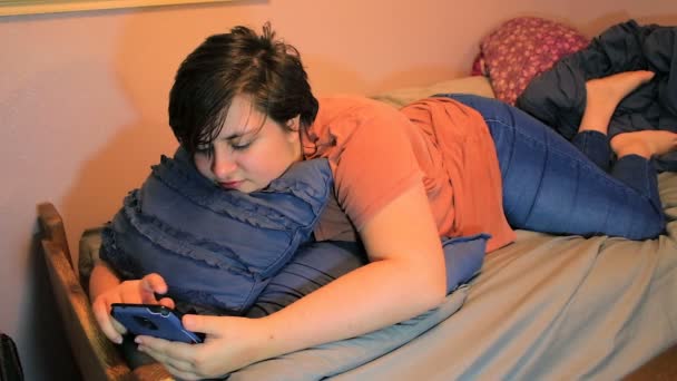 Dziewczyna na łóżku wygląda od telefonu i uśmiecha się — Wideo stockowe