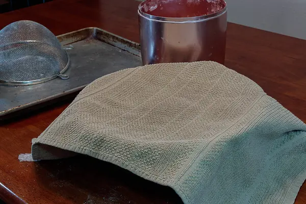 Pan descansando bajo la toalla de cocina en la mesa —  Fotos de Stock