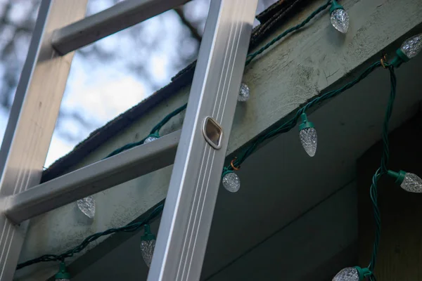 Leiter stützt sich auf Dach, um Weihnachten zu schmücken — Stockfoto