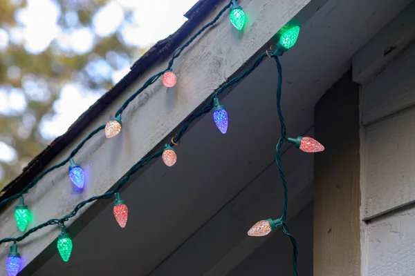 Corda de luzes coloridas sob a borda do telhado — Fotografia de Stock