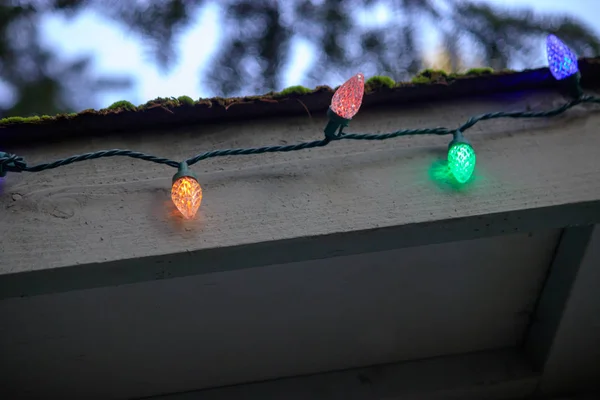 Corda de luzes coloridas ao longo da borda de um telhado — Fotografia de Stock