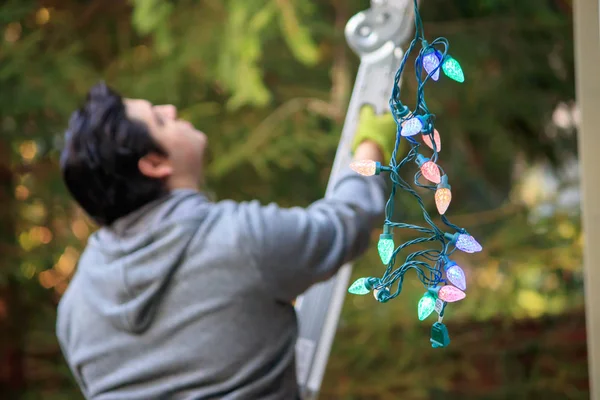 genç adam gri bir merdiven tırmanma noelde süslemek için