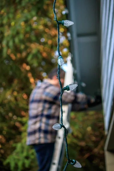 Lumières pendent comme l'homme essaie de décorer la maison — Photo