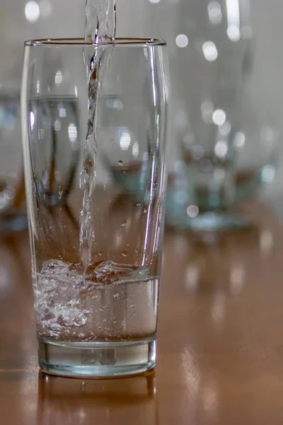 Water poured into tall glass on wood table — Stock Photo, Image