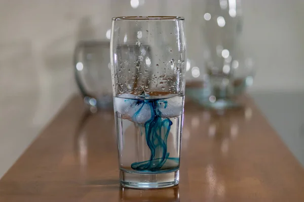 Синє чорнило у склянці на стільниці — стокове фото