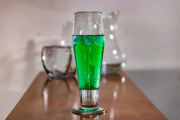 Groene vloeistof in hoog glas op tafel — Stockfoto