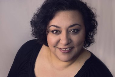 kameraya gülümseyen kıvırcık saçlı brunnete kadın