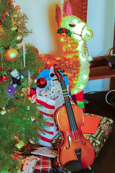 Violen s zabalenými dárky a zdobenými vánočními stromky, světly a ozdobami, osvětlená lama, — Stock fotografie