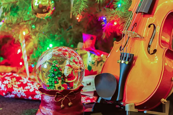 Violen met versierde kerstboom cadeautjes en sneeuwbal — Stockfoto