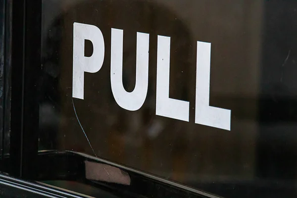 A sign on a business door directing how to get in our out. Pull — Stock Photo, Image