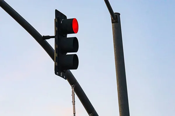 Światło uliczne wiszące na słupie wsparcia świecącym na czerwono — Zdjęcie stockowe
