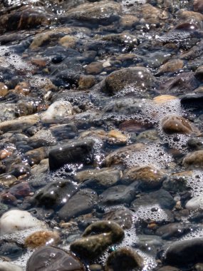 Kayalık kıyı şeridi, taşların üzerinde gelgitler var.