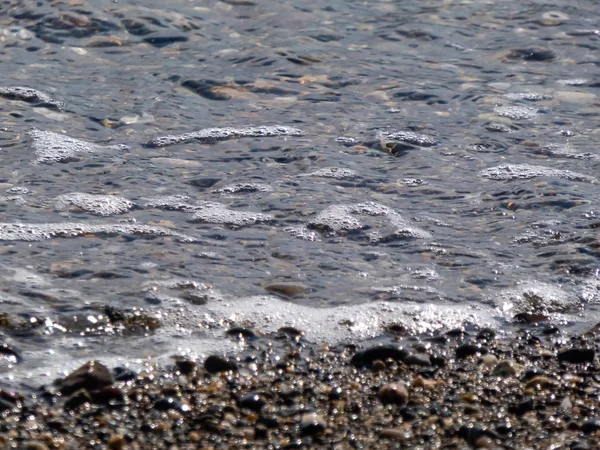 Rotsachtige kustlijn met getij dat in en uit stroomt over stenen — Stockfoto