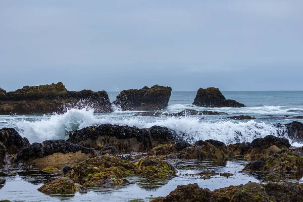 Tidal pools with ocean waves crashing over rocks